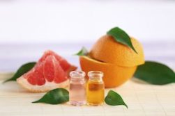 Citrus Scents - Pieces of grapefruit and a halved orange alongside two vials of essential oil