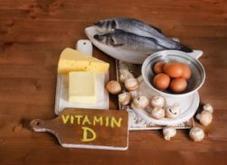 Vitamin D: Foods containing Vitamin D - fish, cheese, eggs, mushrooms - on a wooden surface with a tag stating Vitamin D