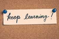 Note tacked to a corkboard saying "keep learning"