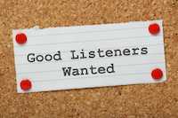 A note tacked to a corkboard with the words Good Listeners Wanted