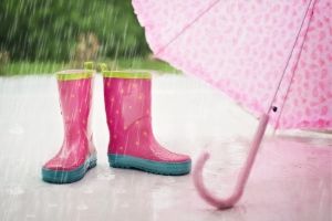 Picture of the rain and a pair of empty pink wellington boots and a pink umbrella