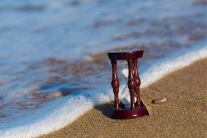 Hourglass on a beach right at the water's edge