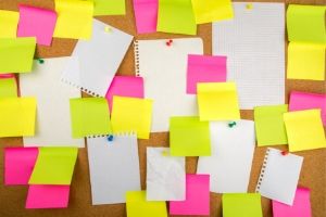 Multiple Post-Its and sheets of blank notepaper pinned to or stuck to a corkboard